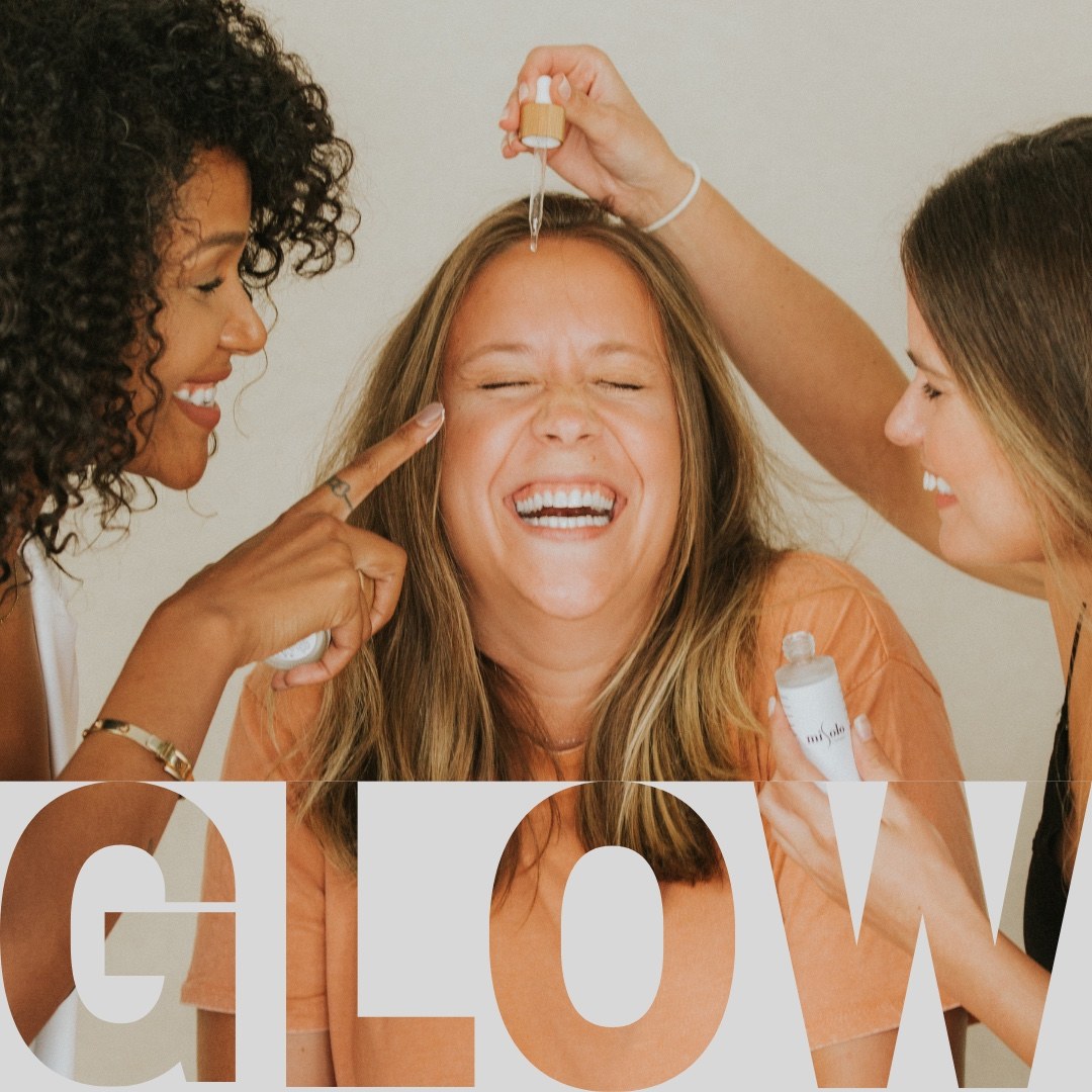 Three women sharing a joyful skincare moment, with the word glow across the image